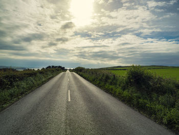 Road amidst green landscape against sky