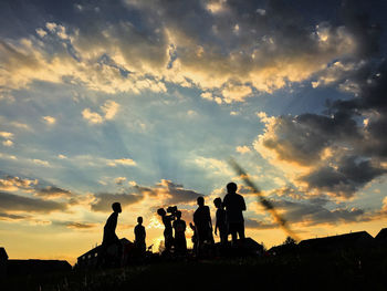 Silhouette people against cloudy sky during sunset