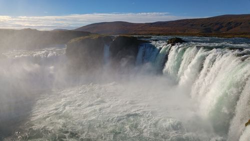 Scenic view of waterfall against sky