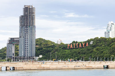 View of buildings by river against sky