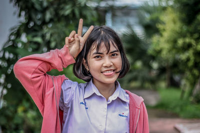 Portrait of cheerful young woman showing peace symbol