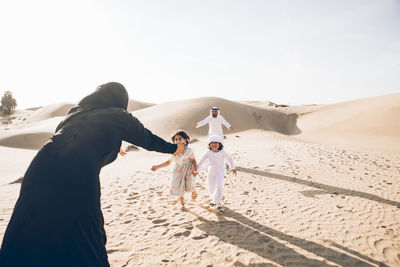 People standing on sand dune against sky