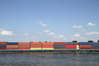 Cargo ship with numerous colorful containers on a river