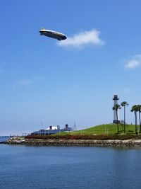 Helicopter flying over sea against blue sky