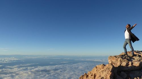 Man standing on rock formation against clear sky