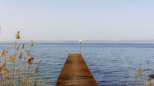 Wooden jetty in lake against clear sky