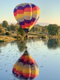 Hot air balloons flying over lake