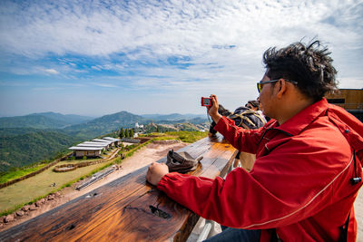 Man photographing while standing against sky