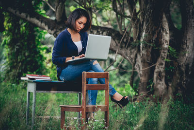 Young woman using mobile phone while sitting on seat