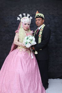 Couple holding hands while standing against wall