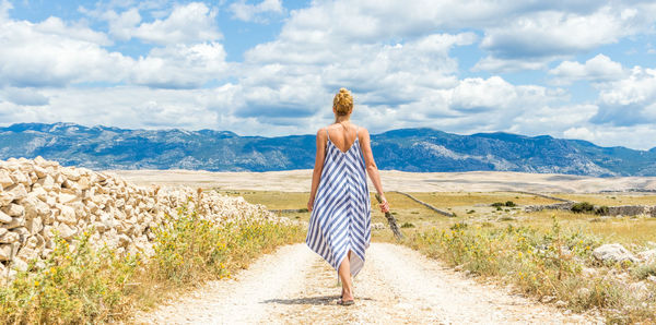 Rear view of woman walking on mountain against sky