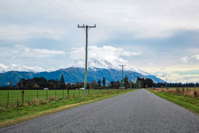 Road leading towards mountains against sky