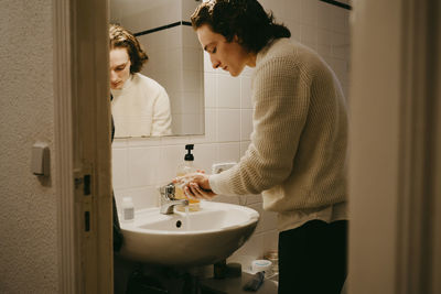 Mid adult man washing hands in bathroom at home