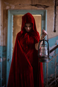 Midsection of woman holding red standing against wall