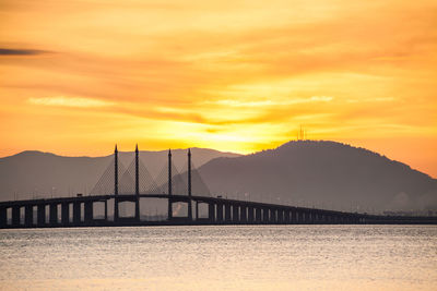 Bridge over bay against sky during sunset