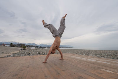 Man doing handstand on pier