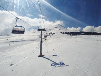 Overhead cable car on snow covered land against sky