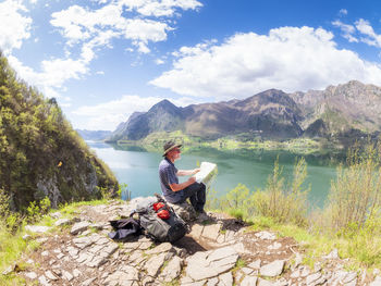 Italy, lombardy, spring at lake idro, hiker sitting with map at observation point