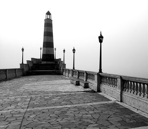 Footpath leading towards lighthouse against clear sky