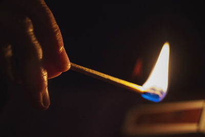 Cropped hand holding lit matchstick