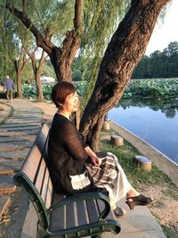 Side view of woman looking away while sitting on bench