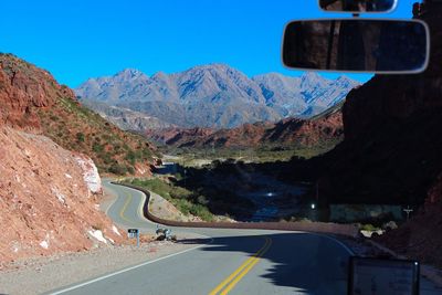 Road leading towards mountains seen through car windshield