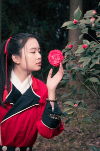 Close-up of young woman holding red flower