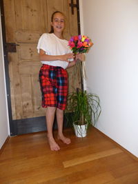 Full length portrait of smiling woman standing against wall