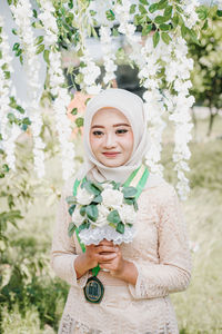 Portrait of a smiling young woman holding flowering plants