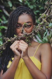 Close-up portrait of young woman holding tree