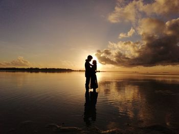 Silhouette woman standing by sea against sky during sunset