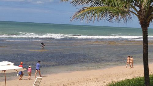 People playing on beach against sea