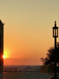 Silhouette street light against orange sky during sunset