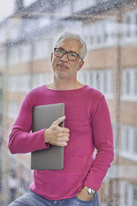 Portrait of mature man holding laptop