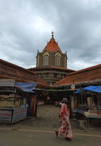 Rear view of people outside temple against sky