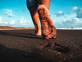 Low section of man standing on beach