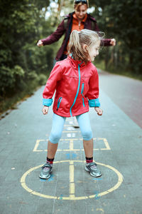 Active little girl playing hopscotch on playground outdoors. jumping for joy