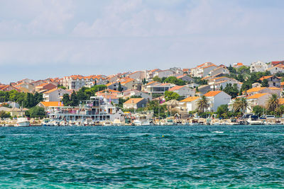 Houses by sea against sky in town