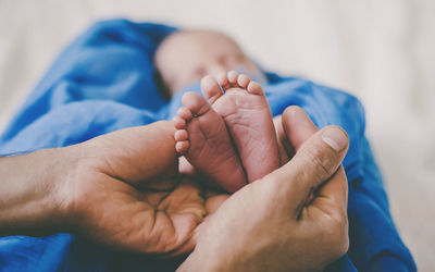 Cropped image of baby on bed