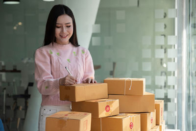 Young female entrepreneur labeling parcel