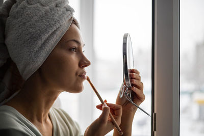 Close-up of woman applying make up at home