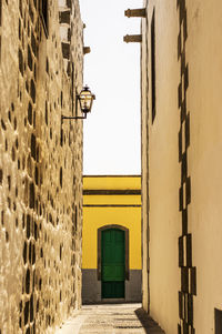 Alley amidst buildings against clear sky during sunny day