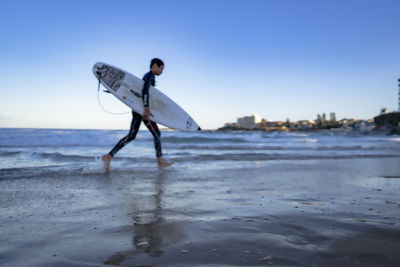 Full length of man on beach against clear sky