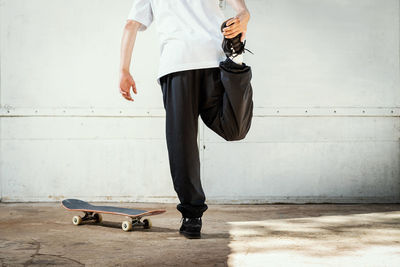 Low section of man skateboarding on skateboard against wall