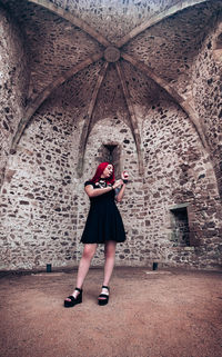 Full length of woman standing against wall