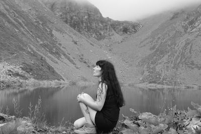 Side view of young woman sitting on mountain