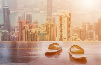 Close-up of modern glass table against buildings in city