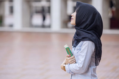 Woman holding kuran while standing in mosque