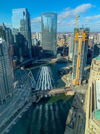 Bridge over river by buildings against sky in city