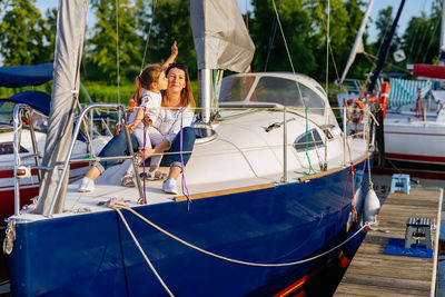 Girl kissing mother sitting on yacht